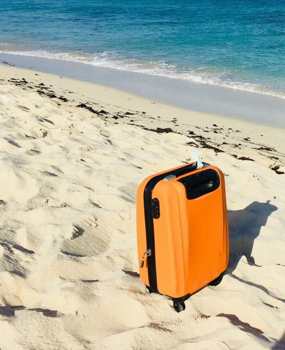 orange and white luggage bag on beach